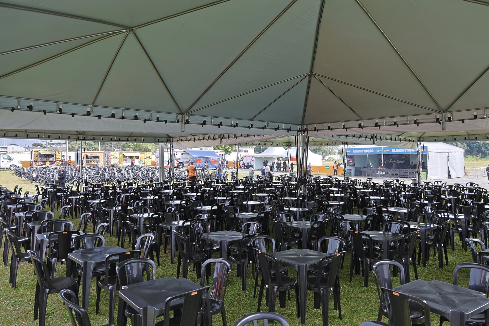 Praça de alimentação coberta com mesas e food trucks